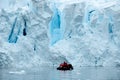 Glacier ice shelf wall in Antarctica, people in Zodiac in front of edge of glacier Royalty Free Stock Photo