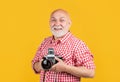glad aged man with retro photo camera on yellow baqckground