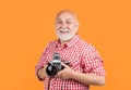 glad aged man with retro photo camera on yellow baqckground