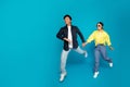 Glad asian couple in casual and sunglasses holding hands, jumping, frozen in air, enjoy walk