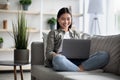 Glad asian lady using brand new laptop at home