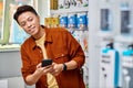 glad asian store owner holding mobile