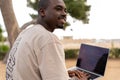 Glad black man with laptop on beach