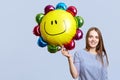 Glad brunette woman wears striped blouse, holds balloon, happy to celebrate daughter`s birthday, meets guests, isolated over blue Royalty Free Stock Photo