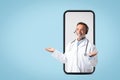 Glad caucasian mature man doctor in white coat, headphones spreads arms to sides, hold free space Royalty Free Stock Photo