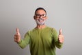 Glad caucasian senior man in glasses shows thumbs up, recommends and advice ad and offer