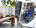 Male forklift driver unloading delivered grapes harvest from truck platform