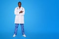 Glad confident handsome young black guy doctor in white coat pointing finger at free space Royalty Free Stock Photo