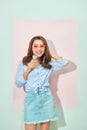 Glad delightful young asian woman with toothy smile looks at camera, holds tasty ice cream, stands on light pink background in Royalty Free Stock Photo