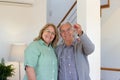 Glad elderly couple showing keys at camera