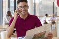 Glad entrepreneur with cheerful expression, wears optical glasses, has telephone conversation, reads newspaper Royalty Free Stock Photo