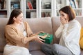 Glad european millennial female gives gift box to surprised girlfriend, congratulate with Birthday