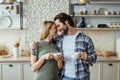 Glad european millennial wife blond and man with stubble drink coffee from cups and enjoy tender moment