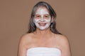 Glad european senior grey-haired woman in towel enjoy spa procedure, face mask