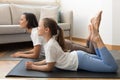 Glad european teenage girl and millennial female in sportswear lies on mat, doing leg exercise, enjoy workout
