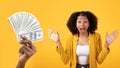 Glad excited millennial black woman with open mouth, shouting, near hand with many money cash