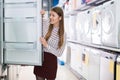 Glad female housewife buying large refrigerator