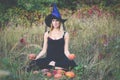 Glad girl in witch costume training lotus pose