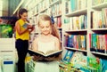 Glad girl in school age looking in open chosen book