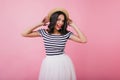 Glad girl in striped t-shirt posing on pink background with funny face expression. Indoor portrait Royalty Free Stock Photo