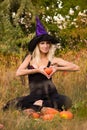 Glad girl in witch costume sitting in lotus pose