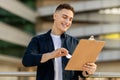 Glad handsome millennial caucasian man engineer businessman, enjoy work with clipboard