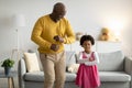 Glad happy african american small girl and old man dancing, have fun in living room interior Royalty Free Stock Photo