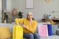 Glad happy pretty caucasian senior woman shopaholic unpacks bags with purchases, sits on sofa Royalty Free Stock Photo
