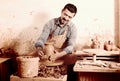 Glad male working with clay on pottery wheel