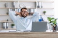 Glad mature european man with beard in glasses with hands behind head resting from remote work behind laptop Royalty Free Stock Photo