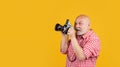 glad mature man with retro photo camera on yellow baqckground