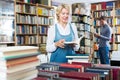 Glad mature woman reading book in book shop Royalty Free Stock Photo