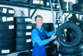 Glad mechanic man standing with new car tires Royalty Free Stock Photo