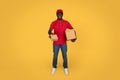 Glad millennial african american guy courier in uniform gives box, deliveryman enjoy work