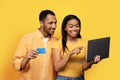 Glad millennial african american husband and wife customers with credit card showing finger at laptop