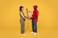 Glad millennial african american man courier in uniform give paper bag with food to adult woman