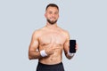 Glad millennial caucasian guy athlete with beard, naked torso, point finger at mobile phone with empty screen