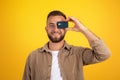 Glad millennial european guy with beard has fun, put credit card to eyes