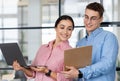 Glad millennial european man show clipboard to arab lady manager