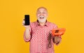 glad old man with retro telephone and modern smartphone on yellow background