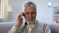 Glad pensioner talking on phone with close relatives, cheap mobile provider Royalty Free Stock Photo