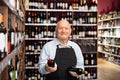 Senior male vintner giving recommendation about purchase wine in his wine house Royalty Free Stock Photo