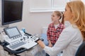 Glad practitioner teaching girl professional aspects in the sonography cabinet