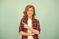 glad redhead woman in checkered shirt pointing finger on blue background