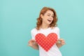 glad redhead woman hold red heart on blue background