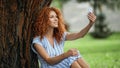 glad redhead woman taking selfie while