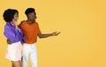 Glad shocked millennial black couple in casual looking at copy space, hold on hand free space