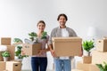 Glad smiling caucasian young family in casual clothes packing belongings, carry cardboard boxes