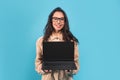 Glad smiling millennial european lady brunette student in casual and glasses showing laptop with blank screen