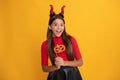 glad teen girl wearing imp horns holding pumpkin party accessory, happy halloween. Royalty Free Stock Photo